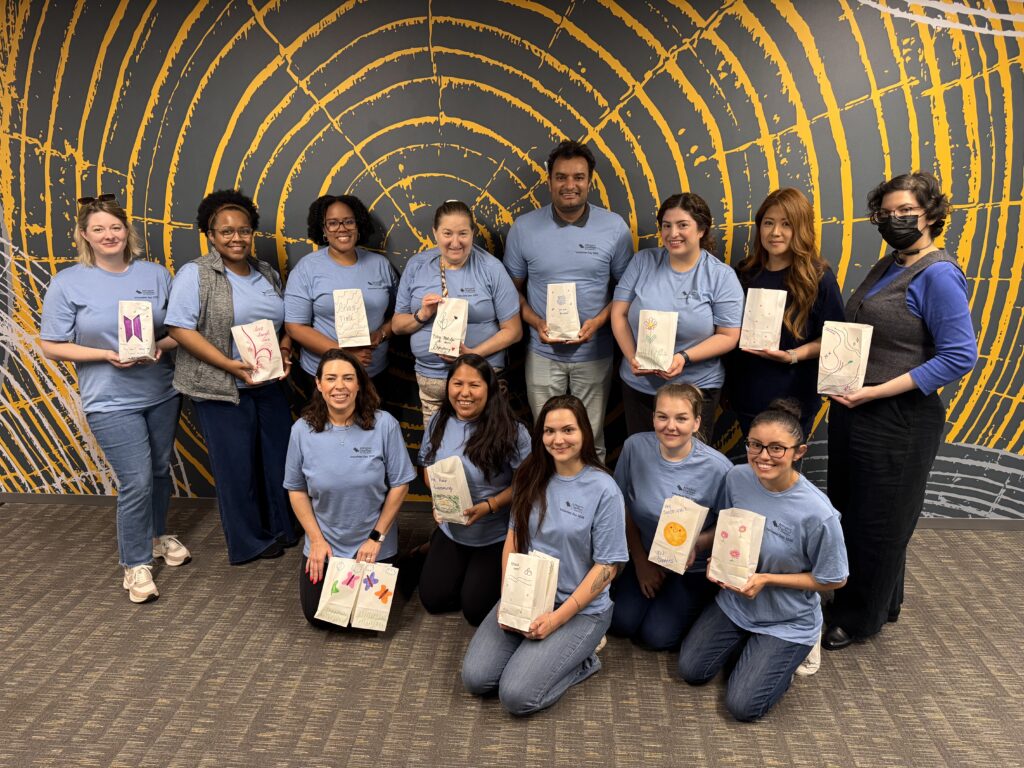 A group of volunteers pose together with kits they made for Doorways clients