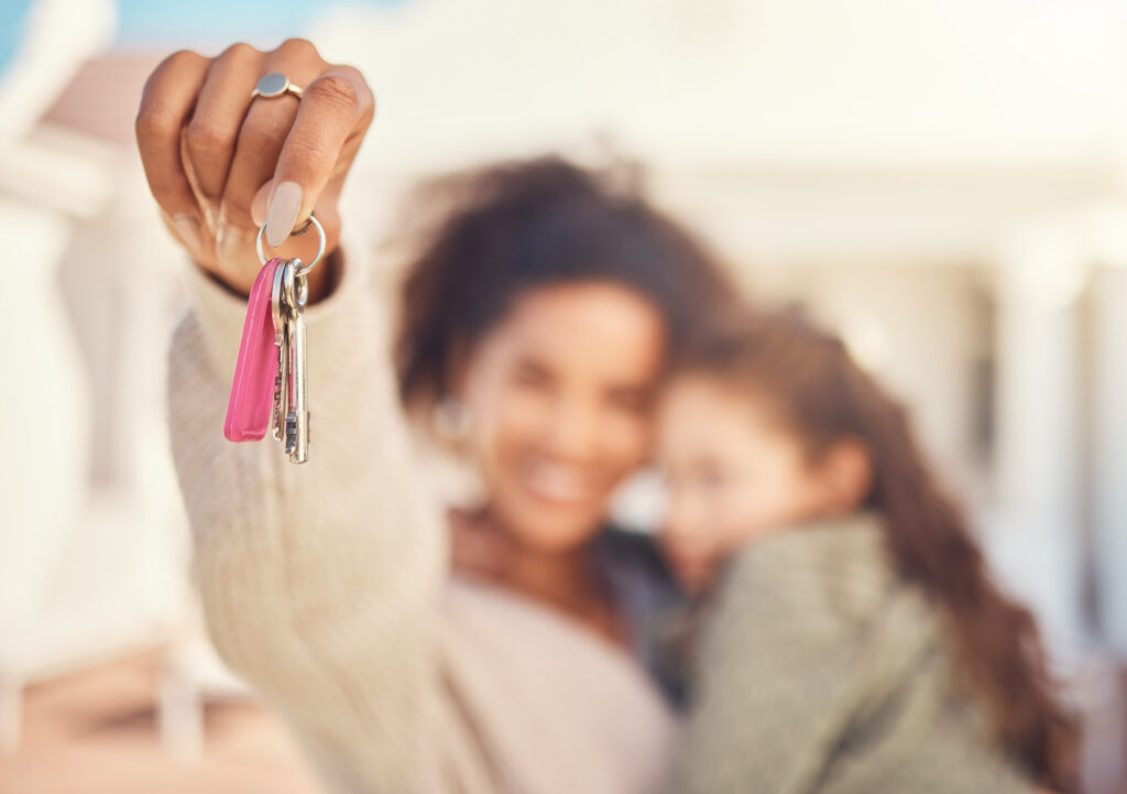 A mom holding her young daughter shows off the keys to their new apartment.