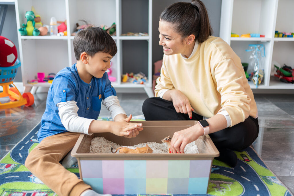 A play therapist facilitates sand-tray therapy with a young child.